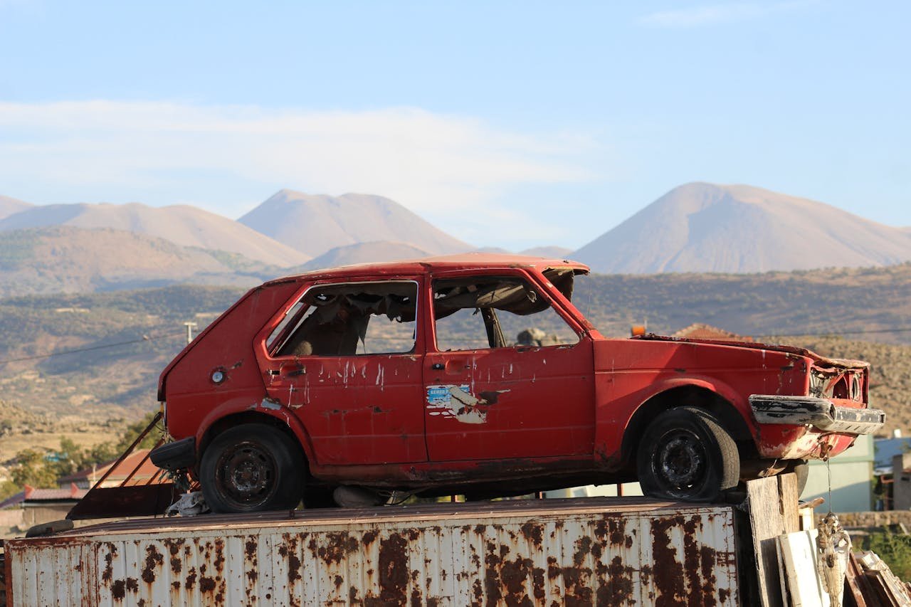 An old red car sits abandoned amidst the picturesque mountains of Kayseri, Türkiye.